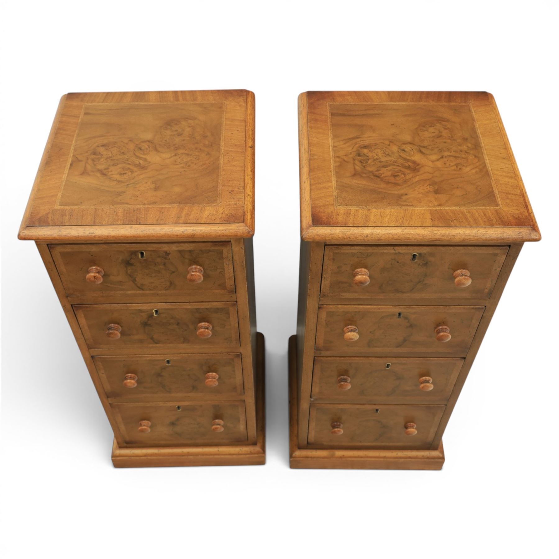 Traditional walnut inlaid pair of tall bedside chests, figured top with inlaid banding, four graduating drawers with wooden turned knobs, raised on a plinth  