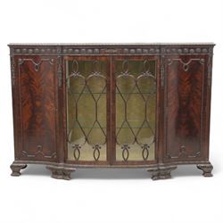Edwardian mahogany serpentine breakfront display cabinet in the neoclassical style, the rectangular top above a carved frieze with roundels, foliage, and ribbon tied swags with central bow-fronted astragal glazed doors enclosing shelves, flanked by panelled doors, raised on bracket feet 