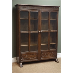  Medium oak bookcase, two glazed and panelled doors with guilloche carved decoration, W107cm, H140cm, D29cm  