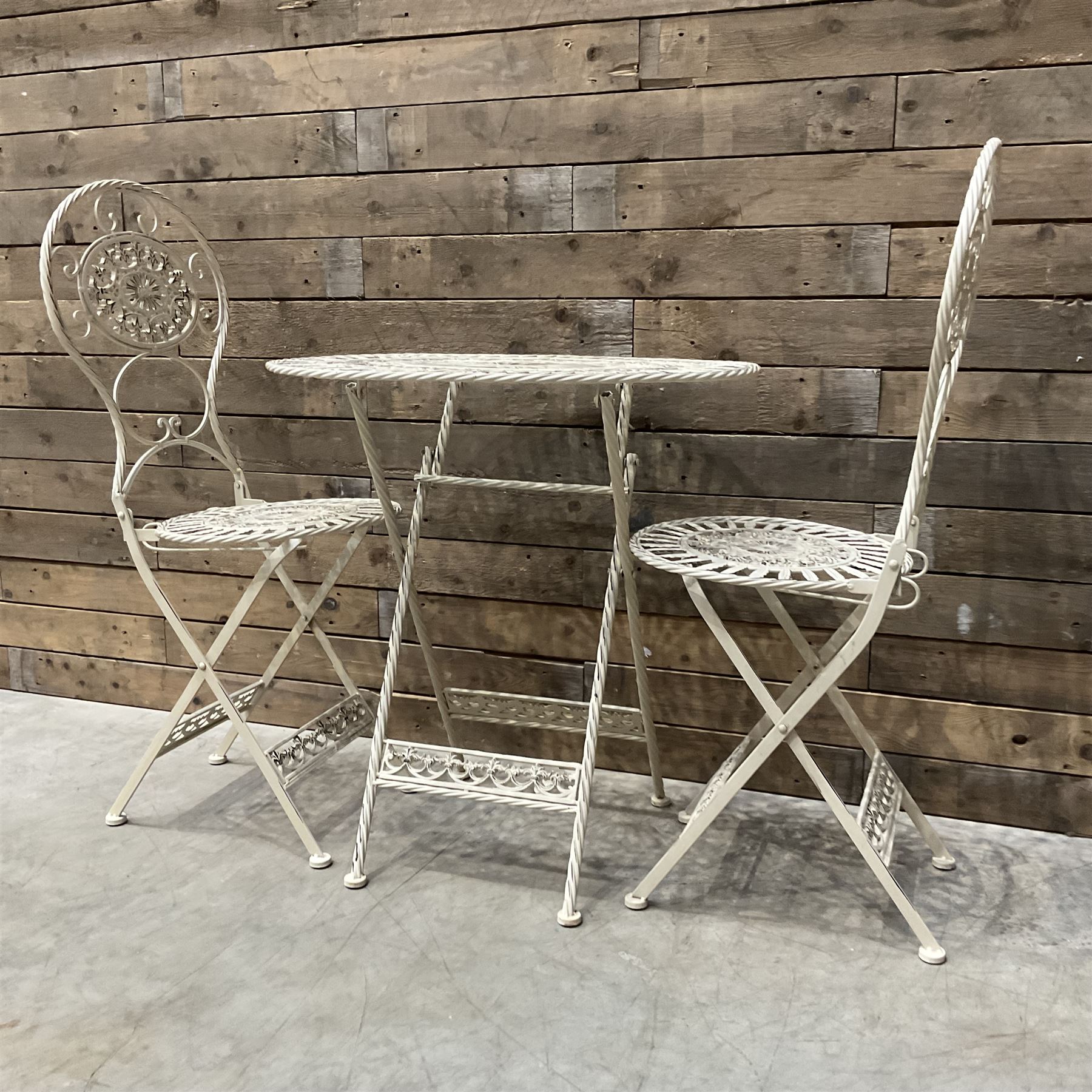 Cast metal bistro set including ornate oval garden table and two matching chairs