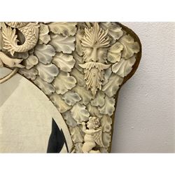 Pair 19th century French Dieppe bone and ivory wall mirrors, the oval bevelled mirror plates within rectangular frames with shaped tops, profusely decorated with ivory leaves, further detailed with carved bone armorial type crest inscribed 'SGOTORVM', putti, fish and mask heads, H81cm W48cm
