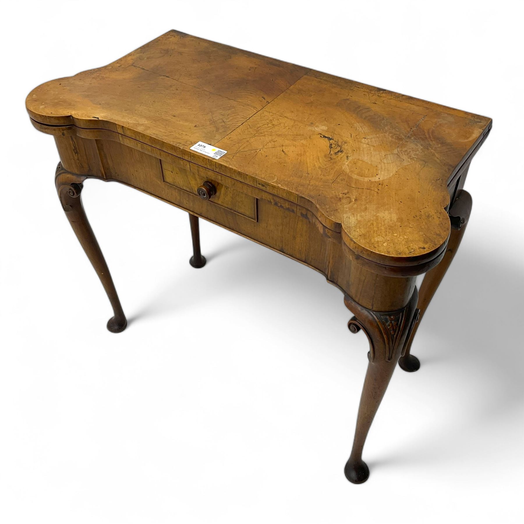Georgian walnut fold-over card table, shaped rectangular top opening to reveal a baize-lined surface, supported by a concertina pull-out rear mechanism, frieze fitted with single drawer, raised on cabriole supports with foliate carvings terminating in pad feet