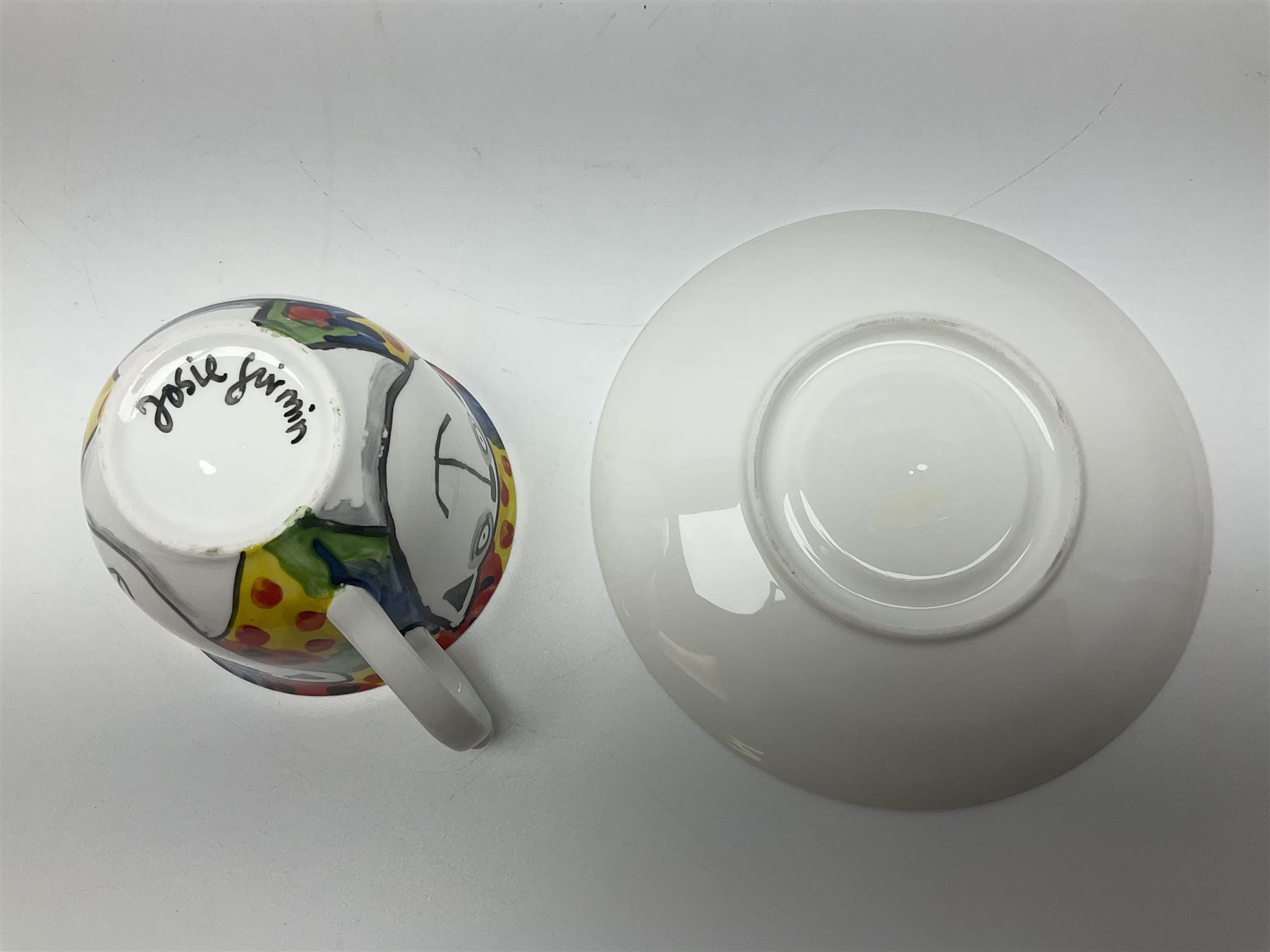 Modern studio pottery by Josie Firmin, to include cup and saucer, three espresso cups and saucers, pair of egg cups etc, each hand painted with varying cartoon cat designs