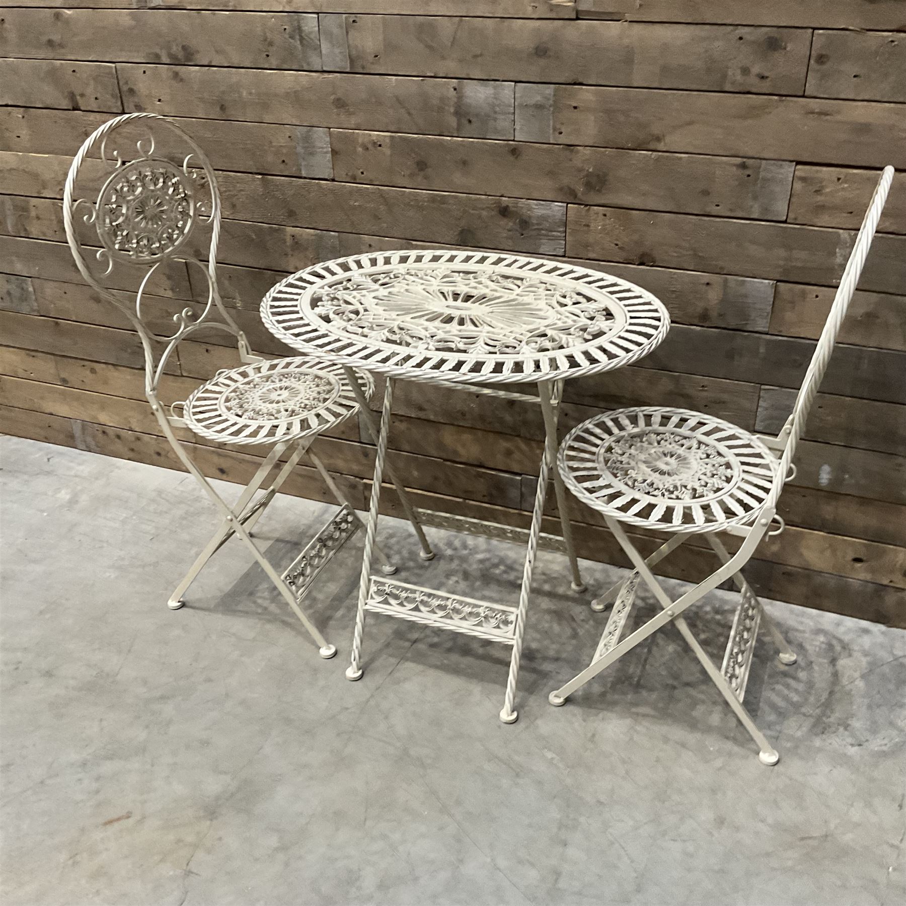 Cast metal bistro set including ornate oval garden table and two matching chairs