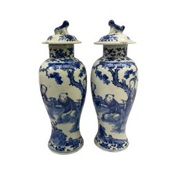 Pair of later 19th century Chinese blue and white vases and covers of baluster form, decorated with figures in a garden setting, with flower and foliate decoration to the neck, the covers with foo dog finials, with six character mark within double concentric circle beneath, H28cm