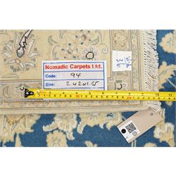 Central Persian Nain hand-knotted rug, sky blue field, with a central cusped medallion in ivory and soft camel tones, issuing an elegant arrangement of scrolling arabesques, palmettes and flowering vines, conforming ivory spandrels, principal pale border decorated with floral sprays and palmettes, flanked by narrow ground borders, with cotton fringe ends  