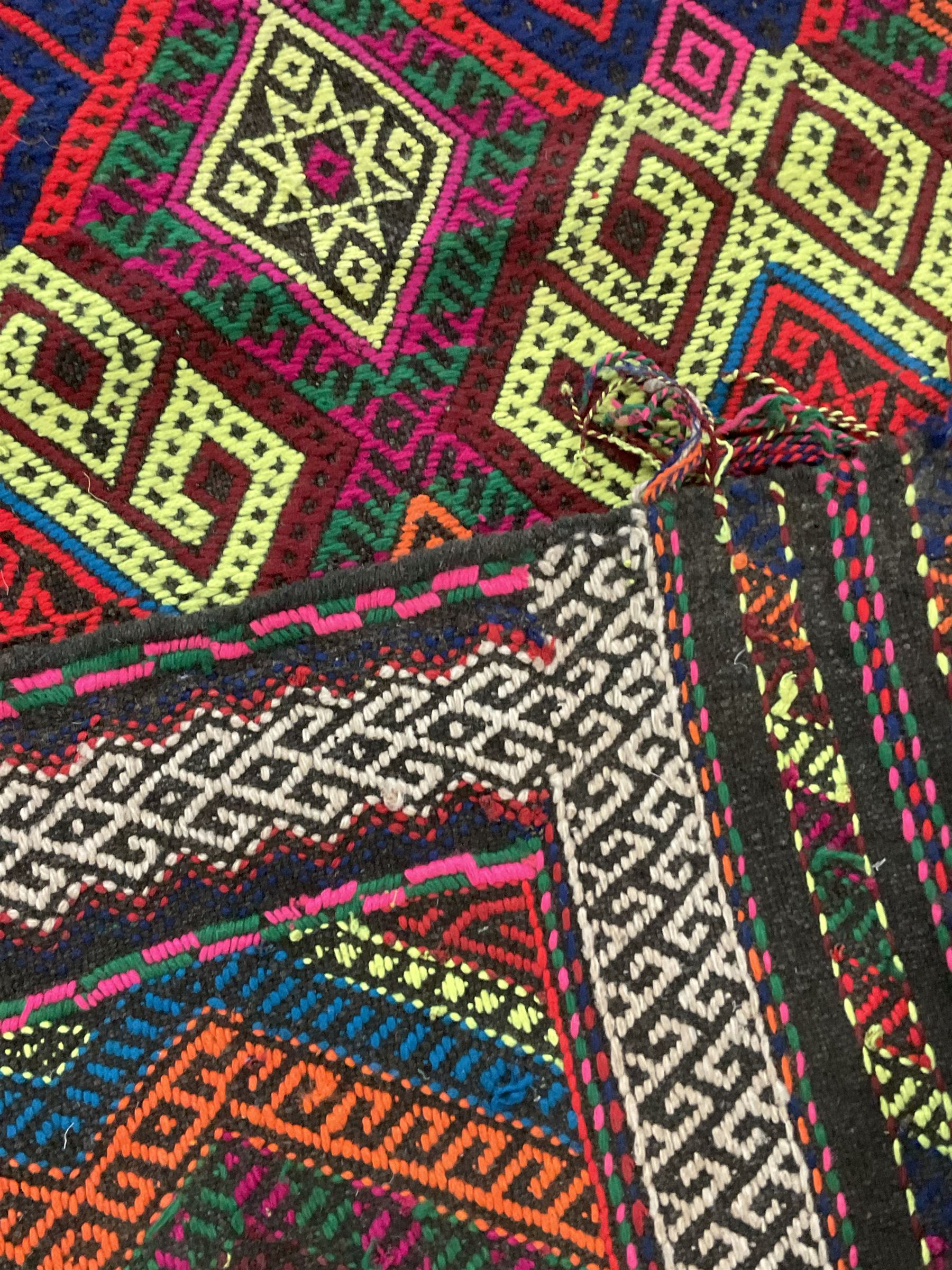 Flatweave geometric design rug, decorated with trailing hooked medallions within zig-zag bands, bright multi-coloured ground 