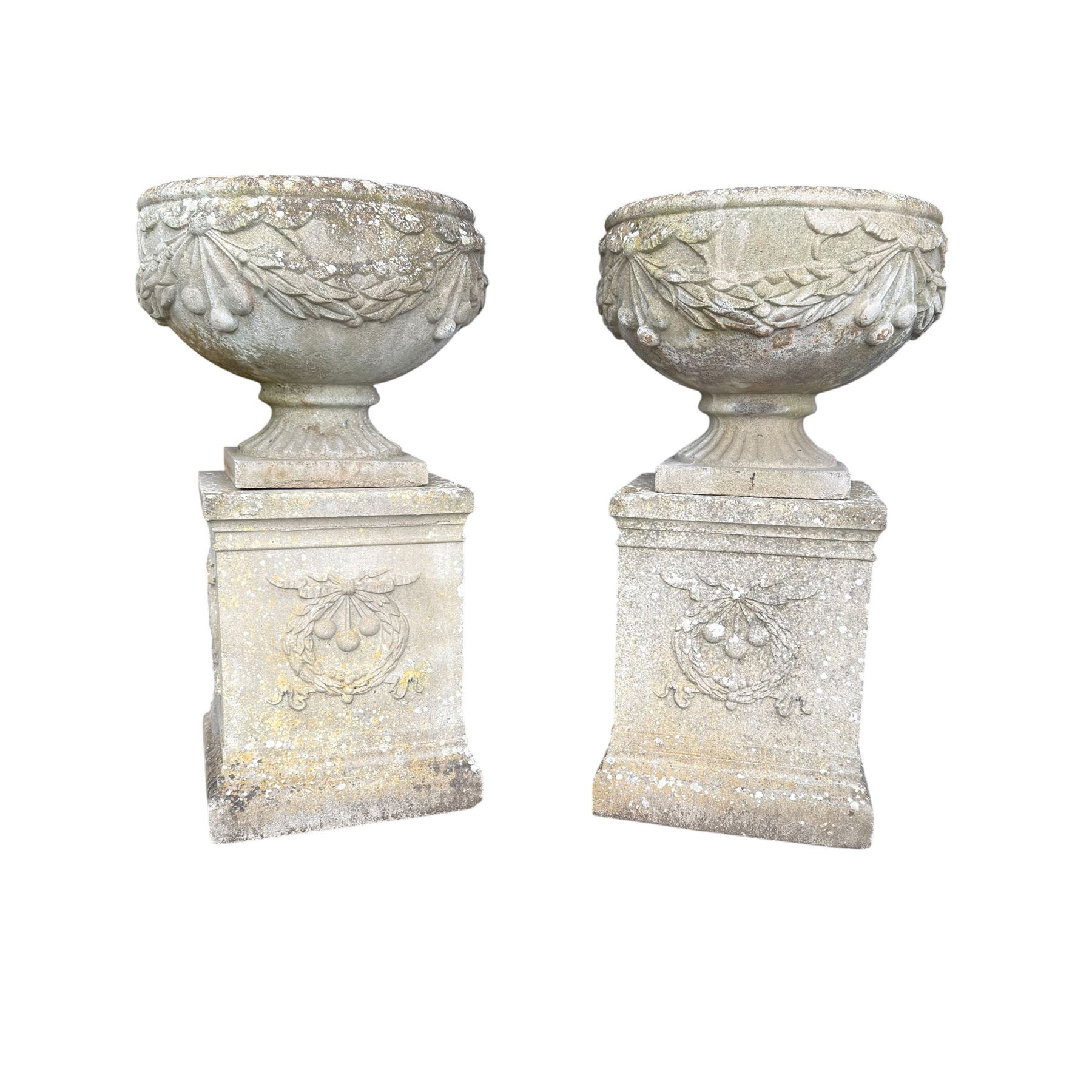 Pair of quality Neoclassical design Haddonstone cast stone garden urns, the globular  body decorated with relief foliate festoons and fruiting motifs, over a fluted socle, the rectangular pedestals with relief foliate wreaths and ribbon garlands