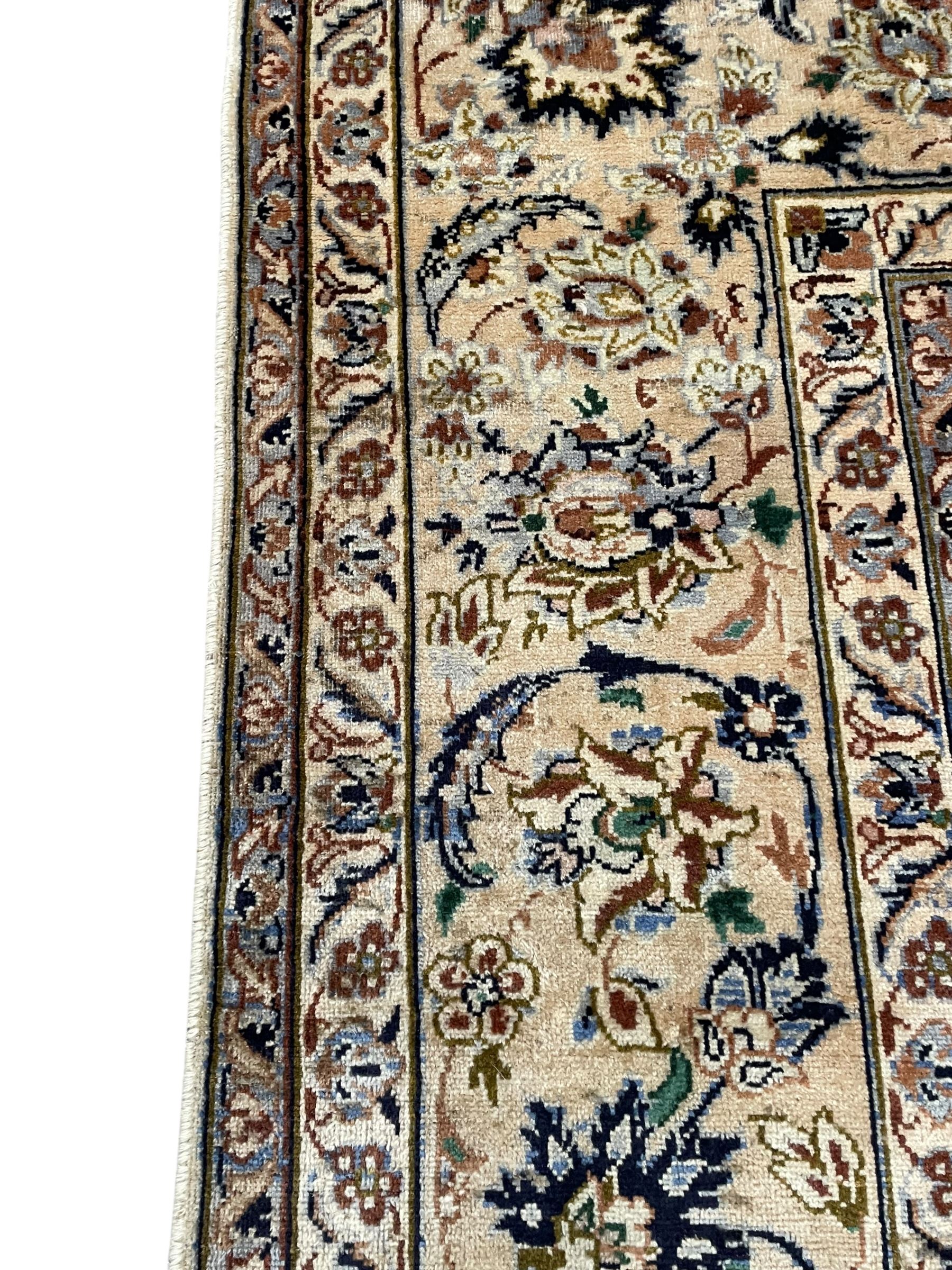Persian Kashan ivory ground carpet, floral design central medallion surrounded by trailing and interlaced leafy branches with palmettes and flower heads, matching patterned border with guard stripes 