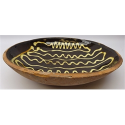  18th century Staffordshire Slipware circular dish, the dark brown ground trailed with wavy formed lines of cream coloured slip and another smaller example, D43cm and D32cm (2)  