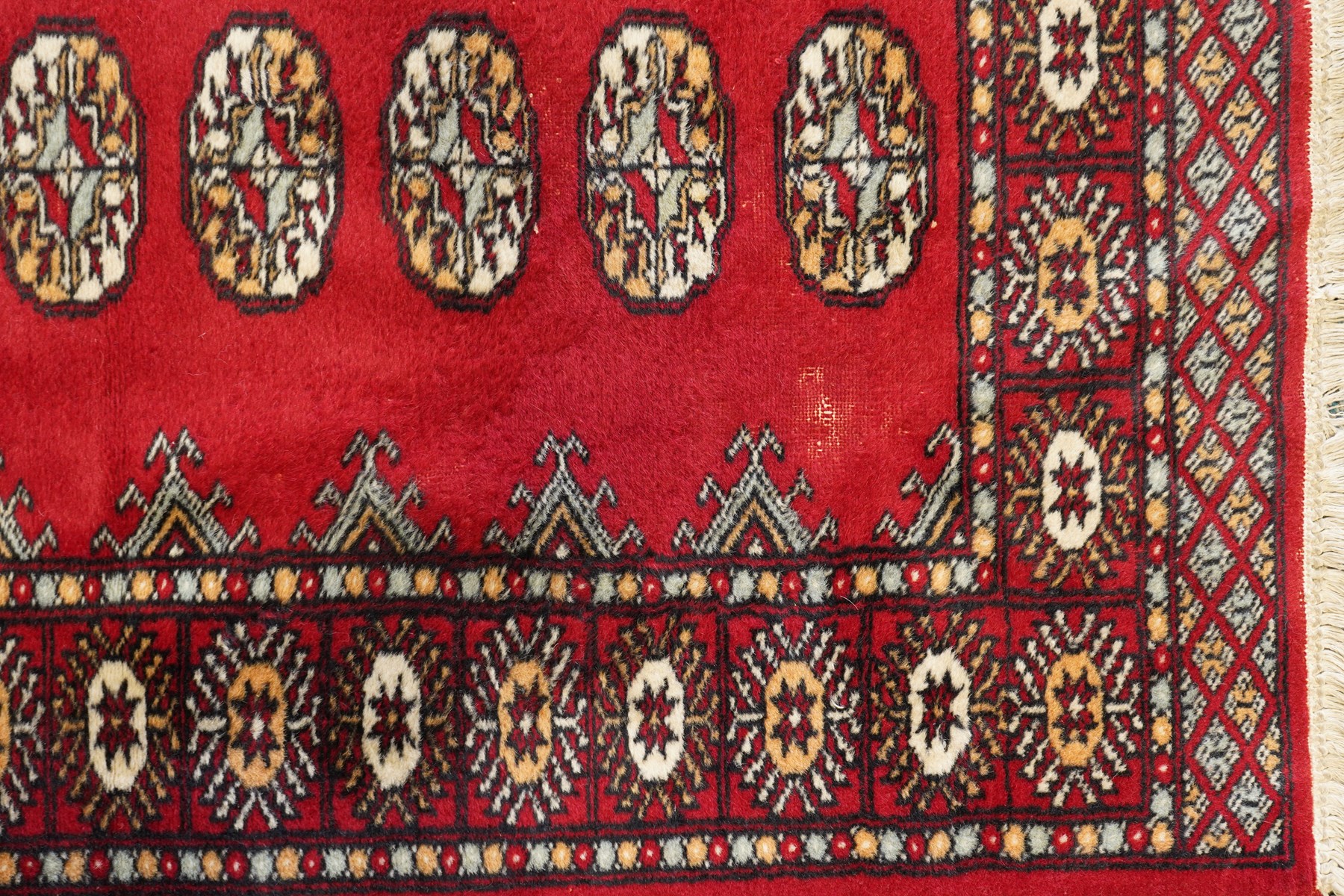 Afghan Bokhara crimson ground carpet, the field decorated with eight Gul motifs with surrounding geometric woven guard bands