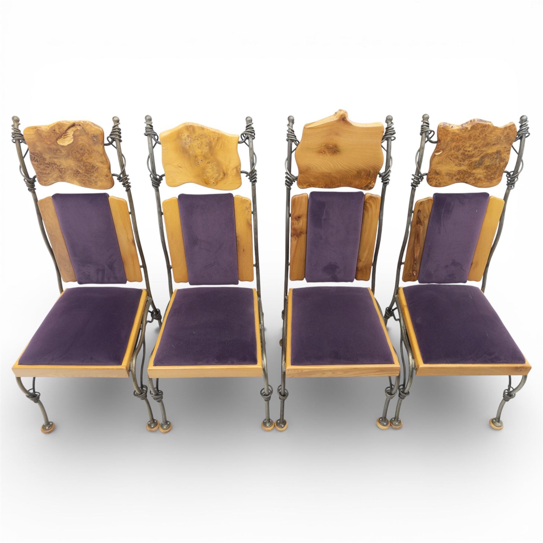 Paul Hodgkiss Designs of Glasgow - contemporary shaped elm dining table with wrought iron base; with set ten (8+2) matching high-back dining chairs, table of organic form above an elaborate wrought iron supports, with central elm stretcher, the chairs with en suite with matching wrought iron work burred elm headrest, purple velour upholstery with drop in seat     

Table: W 102cm, L 243cm, H 74cm
Chairs: W 56cm, D 52cm, H 130cm