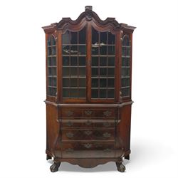 Late 19th century Continental bombe cabinet on chest, shaped moulded cornice with carved cresting, the upper section enclosed by a pair of arched glazed doors with astragal glazing revealing a shelved interior, the lower section fitted with four graduating drawers with rococo-style metal handles, serpentine front and sides, raised on scroll and paw feet