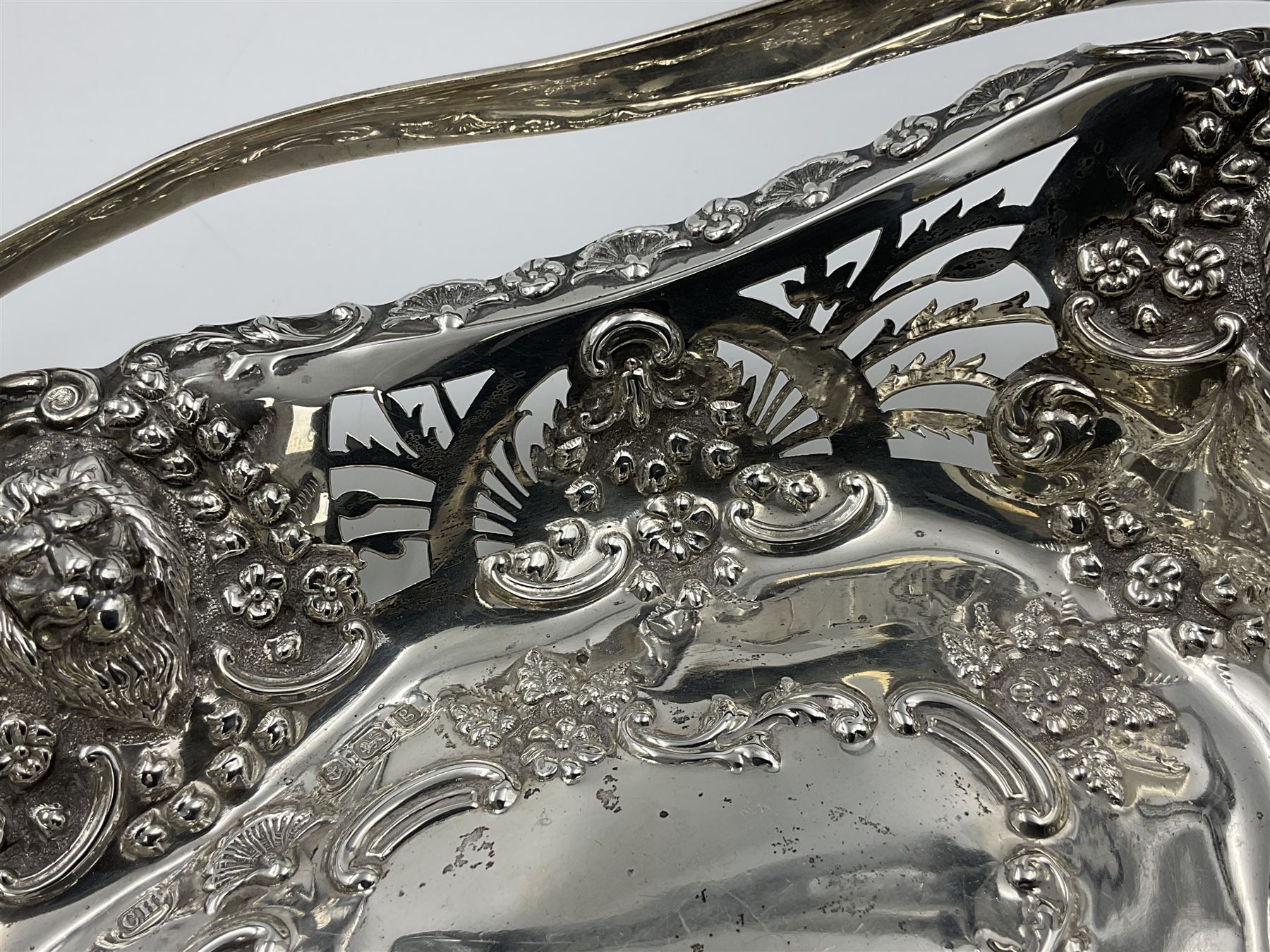 Edwardian silver swing handled basket, of navette form, with four repousse lion masks to each corner and with pierced and embossed floral, scroll and shell decoration to sides, base and handle, hallmarked Charles Horner, Birmingham 1906, height including handle H20cm