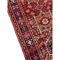 Persian Karajeh red ground runner, the field set with six trailing geometric medallions outlined in ivory, field decorated with stylised shapes, thick band with repeating pattern and multi-border