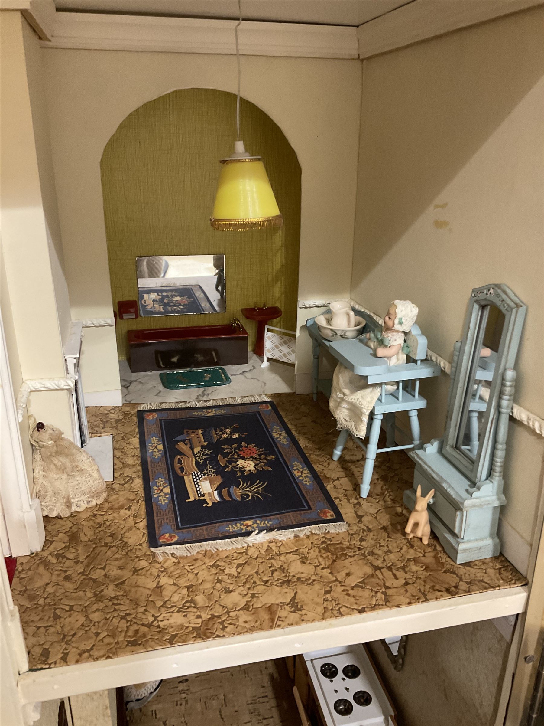 Kit-built wooden dolls house, possibly by Honeychurch, as a 19th century style double fronted two-storey residence; with stucco walls and flat roof with circular skylight and parapet with balusters; central door with fanlight, Corinthium columns and balcony over; simulated sash windows to three sides; hinged front facade opening to reveal a partially furnished interior with central hall, stairs and landing, two ground floor rooms and two first floor en suite bedrooms; wired for electric lighting W69cm H70cm D41cm