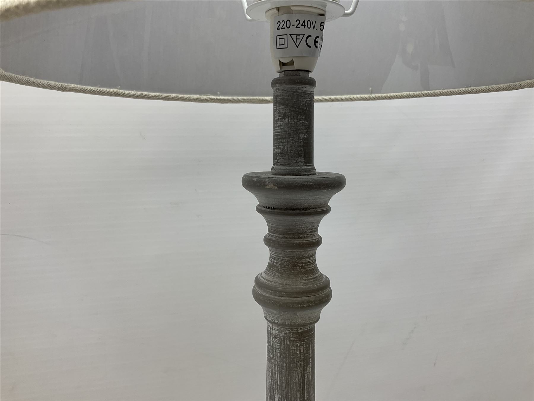 Pair of composite grey washed table lamps with a slender column upon a circular foot with natural linen shades