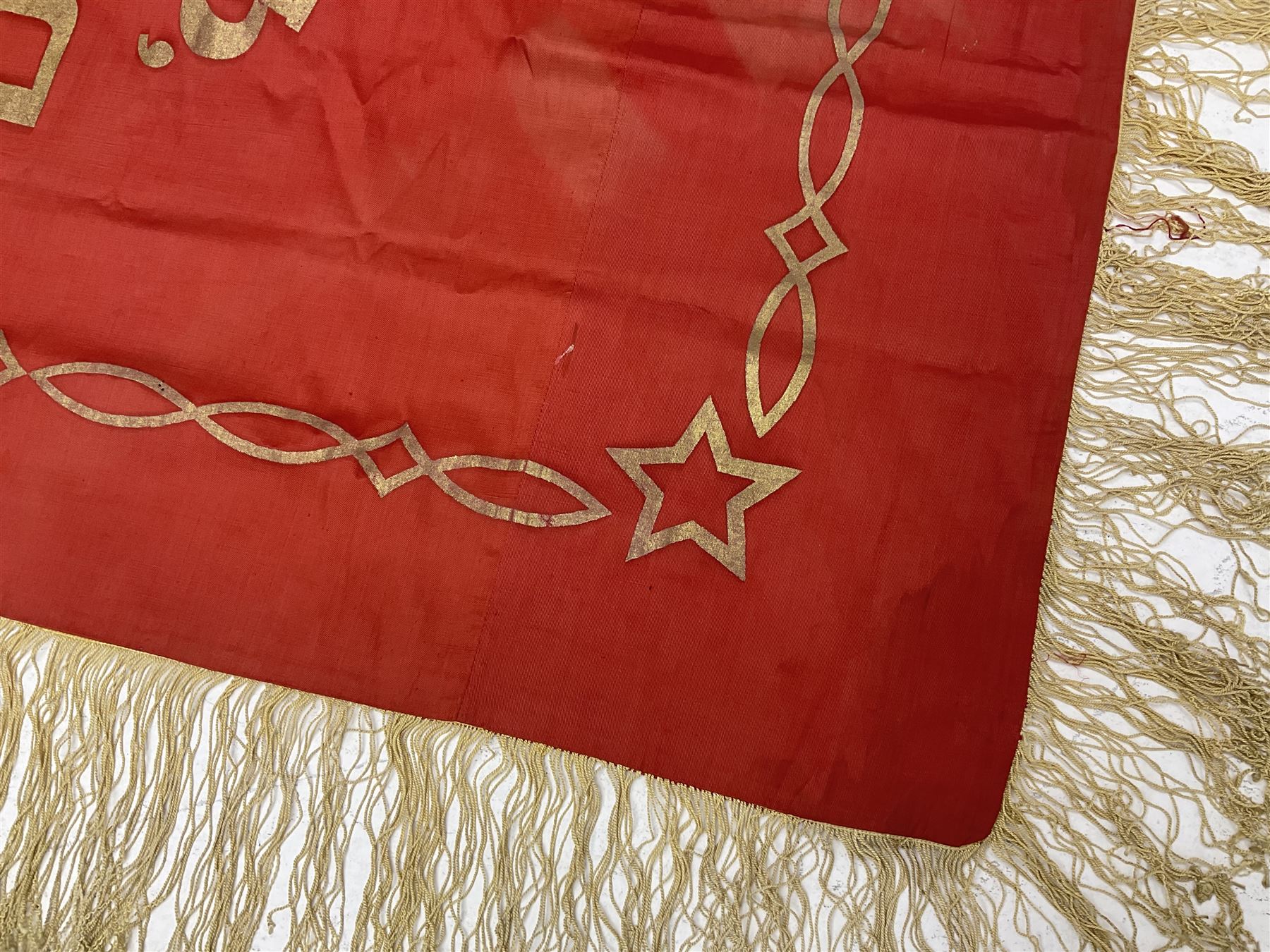 1970s Soviet banner printed in gold on a red ground, roughly translates as 'Transferable Banner - To the winner in the Socialist Competition' and 'Work Study Live by Communism' verso; wreath of wheat ears to either side; tassels on three sides 110 x 155cm