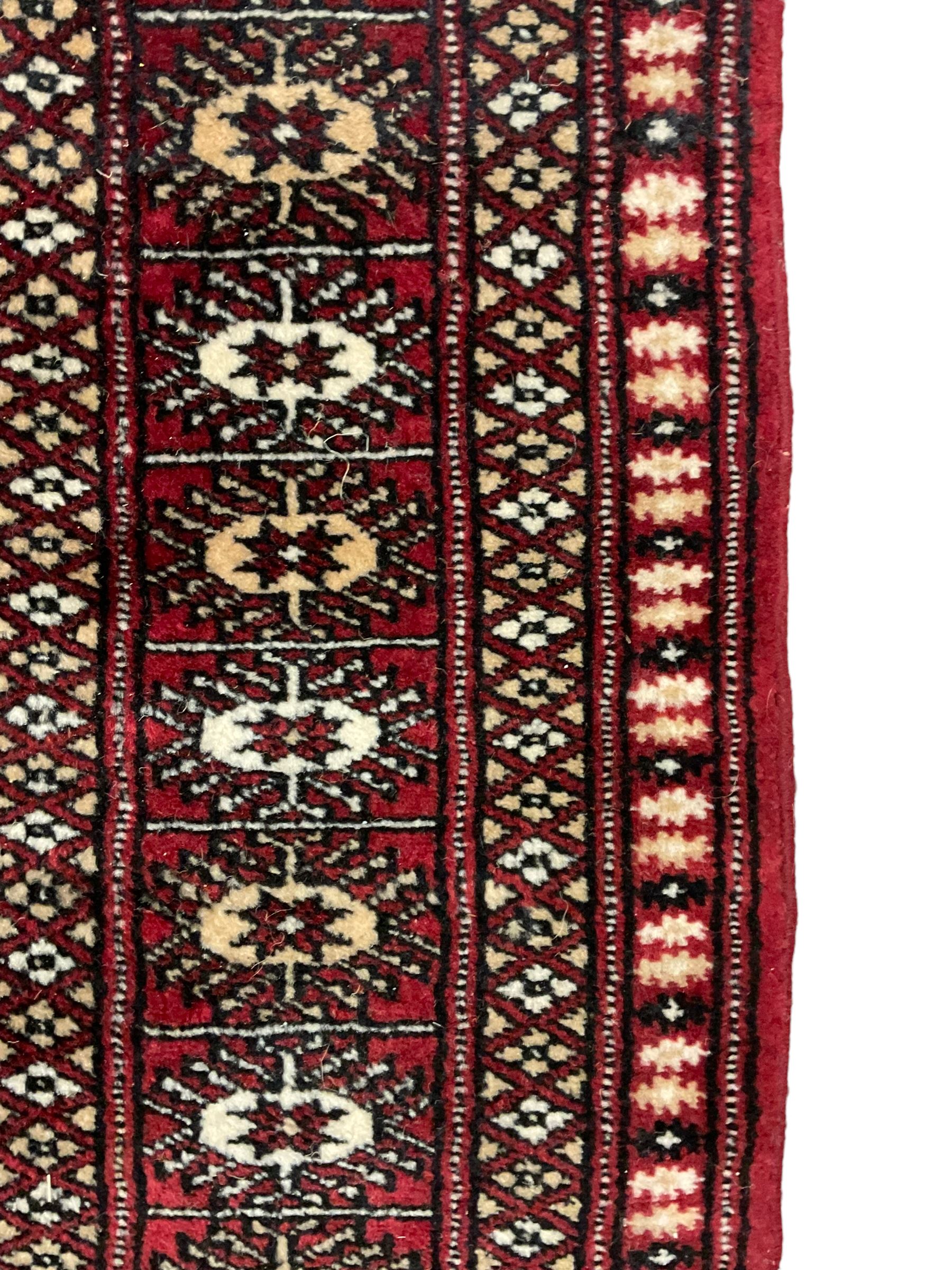 Persian Bokhara rug, red ground and decorated with single row of Gul motifs, multiple band border with geometric design