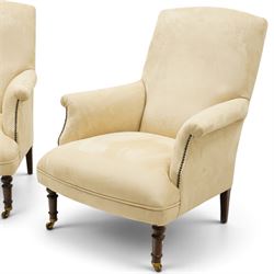 Sofas & Stuff - pair of ‘Thistle’ armchairs upholstered in neutral fabric, each with gently sloping back, padded scroll arms with close-set stud detailing, loose seat cushions, raised on turned wooden legs with brass castors