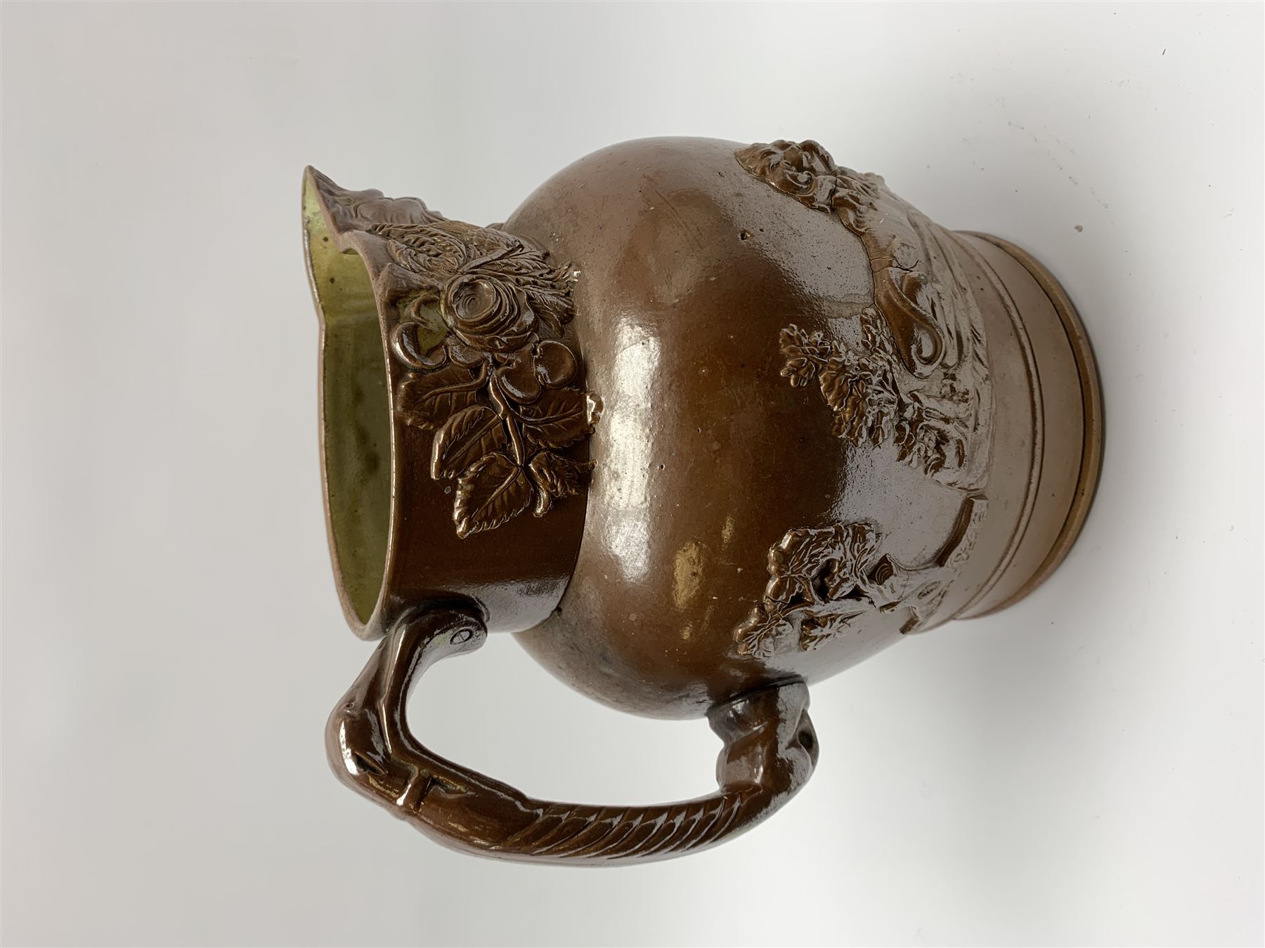 19th century salt glazed stoneware jug, with mask spout and greyhound modelled handle, the body decorated in relief with Royal Coat of Arms flanked by lions, the rim with the flowers of the union, roses, thistles and shamrocks, H26.5cm