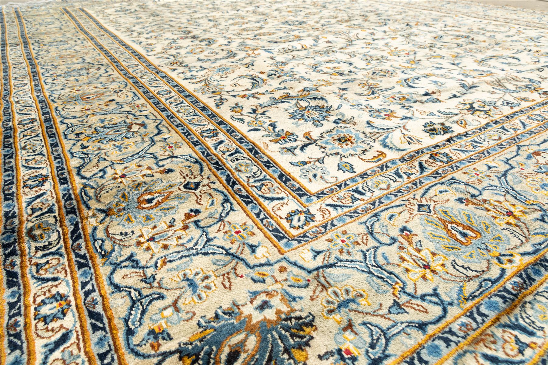 Central Persian Kashan hand-knotted carpet, ivory field profusely decorated with an all-over scrolling vine, palmette, and lotus design in shades of soft blue, pale gold, and green within floral borders