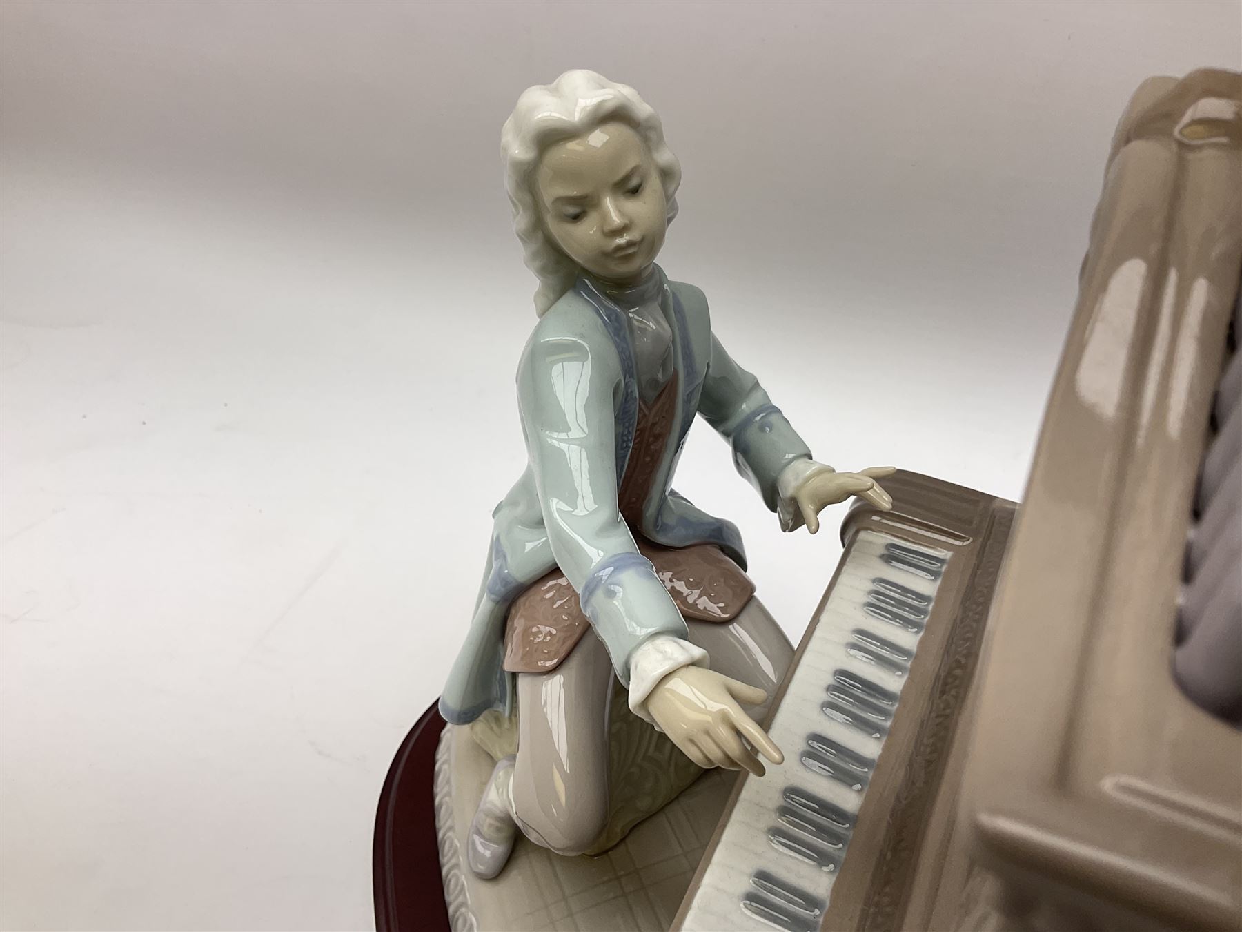 Lladro figure, Young Bach, modelled as a young Johann Sebastian Bach playing the piano, on a mahogany oval base, limited edition 2348/2500, in original box, no 1801, year issued 1994, year retired 1995, H29cm