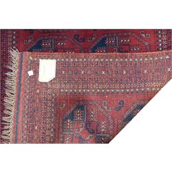 Afghan red ground Bokhara rug, the field decorated with two rows of large Gul motifs, within geometric pattern borders 