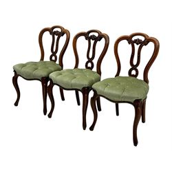 Set of six carved Victorian walnut balloon back dining chairs, button upholstered in green velvet fabric, back with foliate carved decoration supported on scroll form legs 