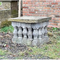 Weathered stone garden table, comprising twenty reconstituted stone balustrades supporting a stone flag top. H55cm, 63cm x 77cm.  - COLLECTION BY APPOINTMENT FROM: The White House, Thirsk Road, Easingwold, York, YO61 3NF - CALL 01723 507111 TO ARRANGE