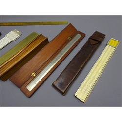  Troughton and Simms 'English Foot' steel rule in fitted mahogany case, a brass scale rule and triangular scale rule, two Faber Castell slide rules in leather cases, and a folding music or book stand, (6)  