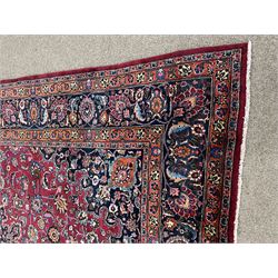 Persian Meshed carpet, plum ground and decorated with stylised flower heads and interlacing foliate, large central stylised medallion with orange detail, the orange mirrored in the five band border decorated with scrolling floral design, signature panel to end 