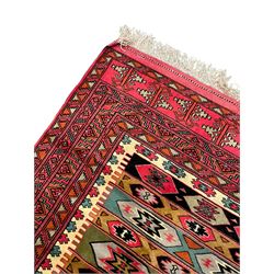 Turkaman red ground rug, the field divided into horizontal rows and decorated with geometric motifs, intricately pattern borders and end panels