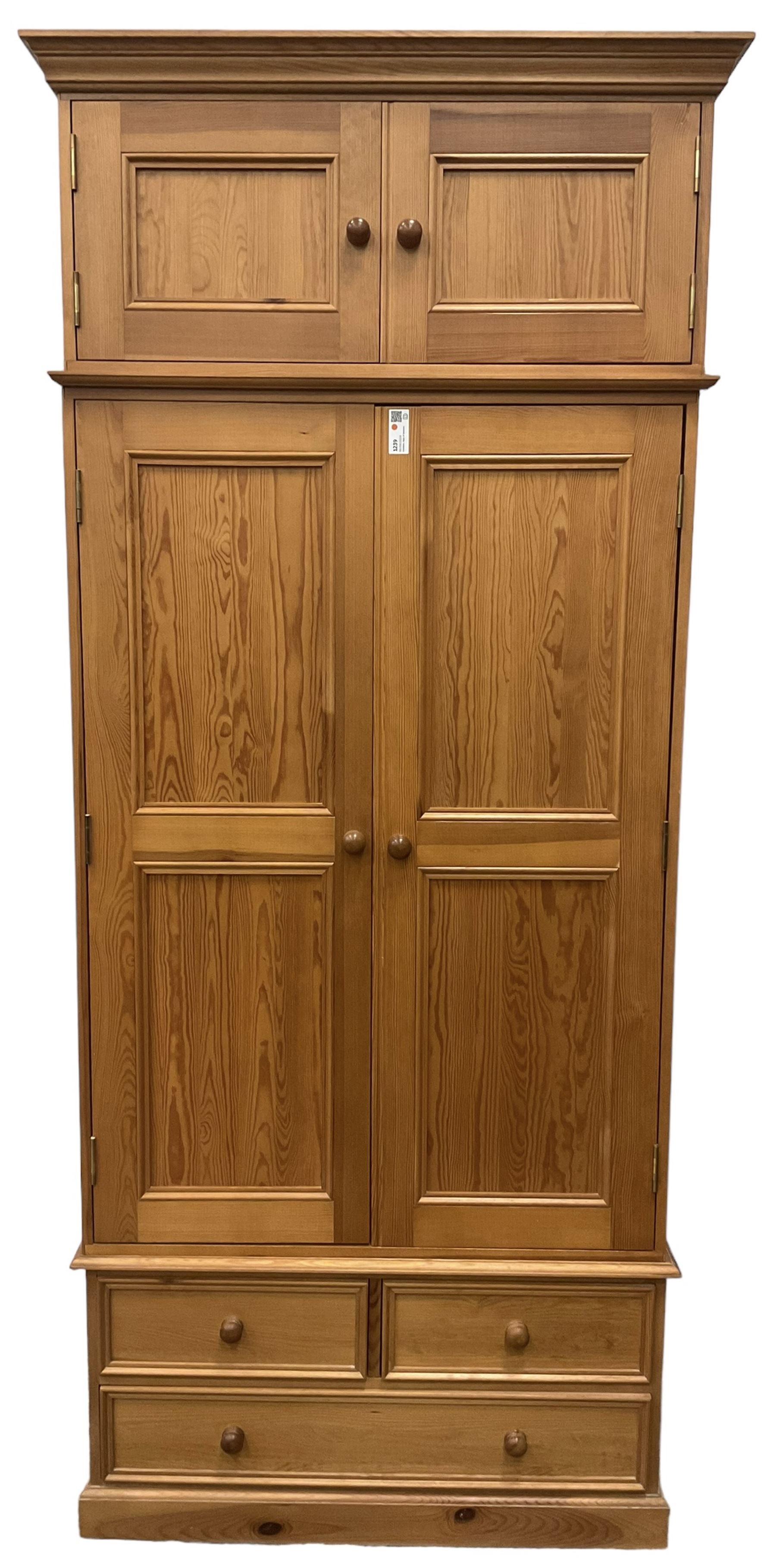 Solid pine double wardrobe, fitted with top box, enclosed by panelled doors, two short and one long drawer, on plinth base 