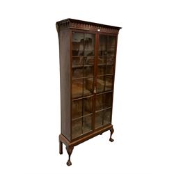 George III mahogany bookcase on stand, the projecting arcade carved cornice with turned split spindles, fitted with two astragal glazed doors enclosing five adjustable shelves, the stand with cartouche and scroll carved cabriole supports terminating in ball and claw feet