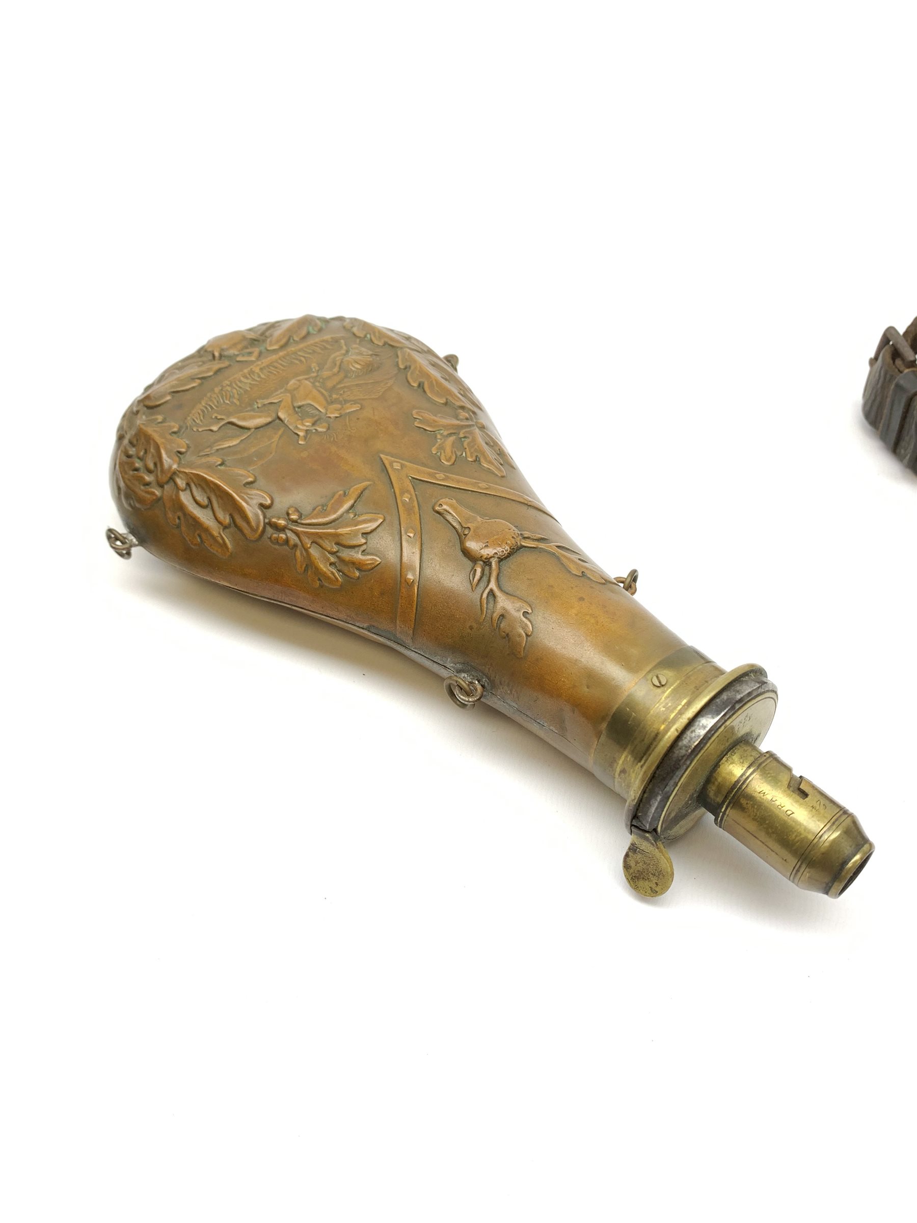Victorian large copper powder flask embossed with a hunting scene within an oak leaf border with stag and fox heads, the nozzle marked 'Extra Quality Sykes Patent', fitted with four suspension rings H24cm; together with Victorian leather shoulder shot flask with Sykes nozzle L80cm (2)