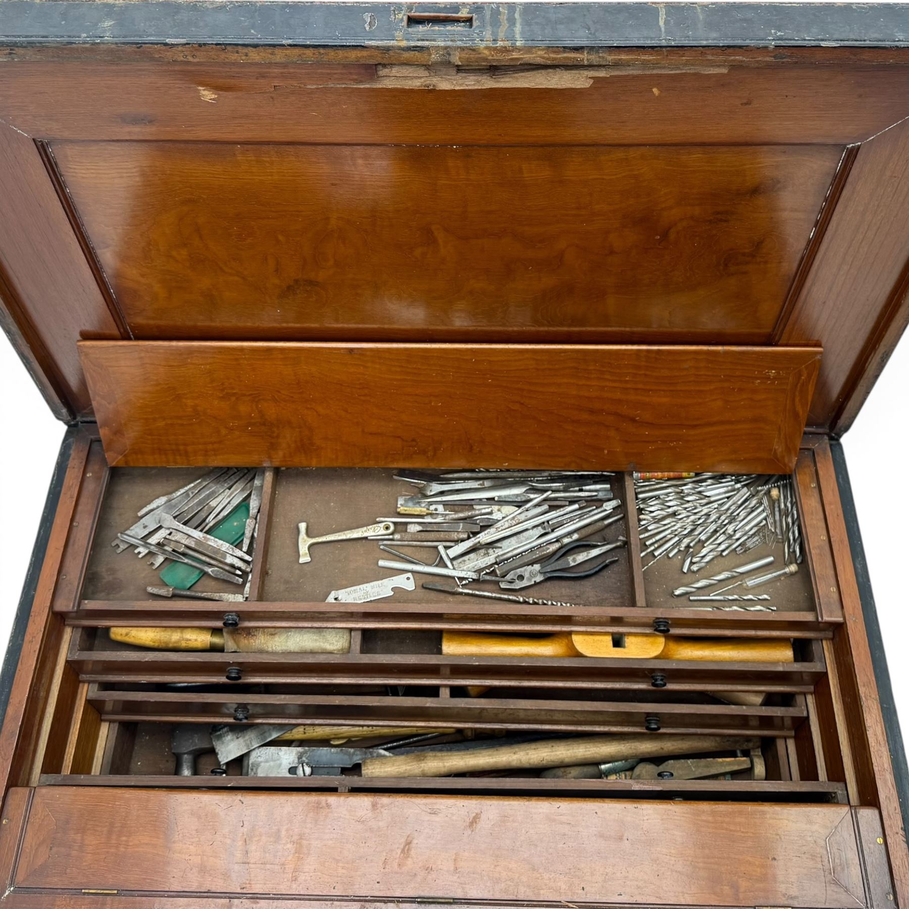 20th century black painted camphorwood lined tool chest, rectangular hinged lid over moulded edge, black painted exterior with iron straps and carry handles, the interior fitted with sliding lidded trays and drawers with turned handles, containing an assortment of hand tools