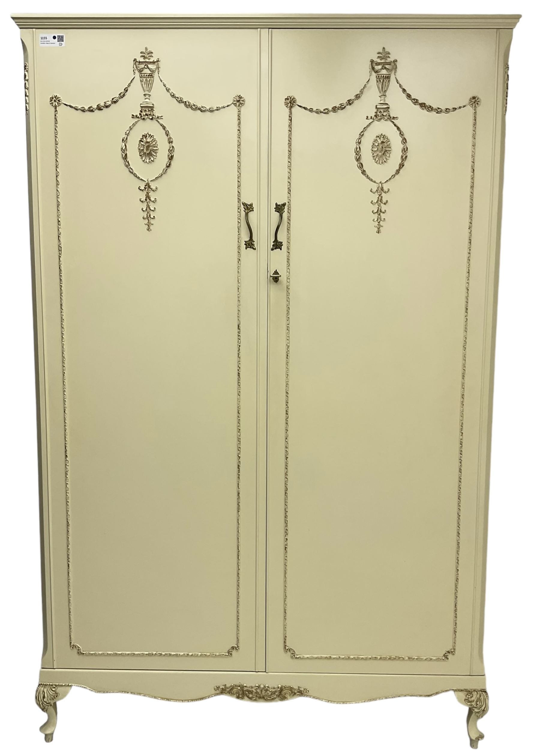 French classic design cream painted double wardrobe, the doors decorated with gilt and cream applied urn motifs with extending bell-flower festoons and ribbon twists, enclosing shelf and hanging rail, shaped apron on acanthus cabriole feet