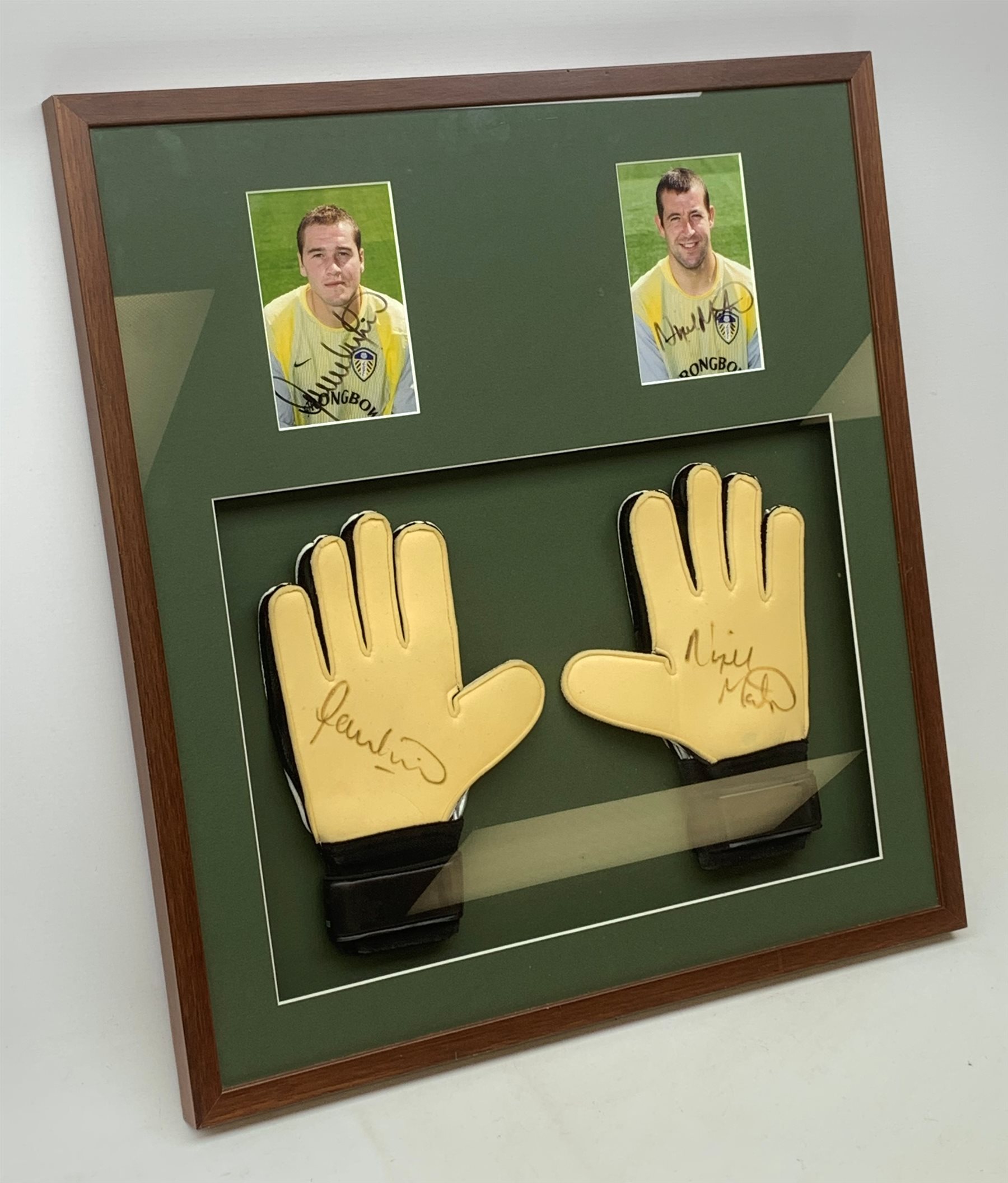 Pair of 1990s Leeds United goalkeeper's gloves signed by Nigel Martyn and Paul Robinson, mounted in a wall hanging framed display with signed pictures of each player 60 x 55cm. Provenance: the vendor was a coach at the keepers' club Leeds United and the gloves were signed for him.