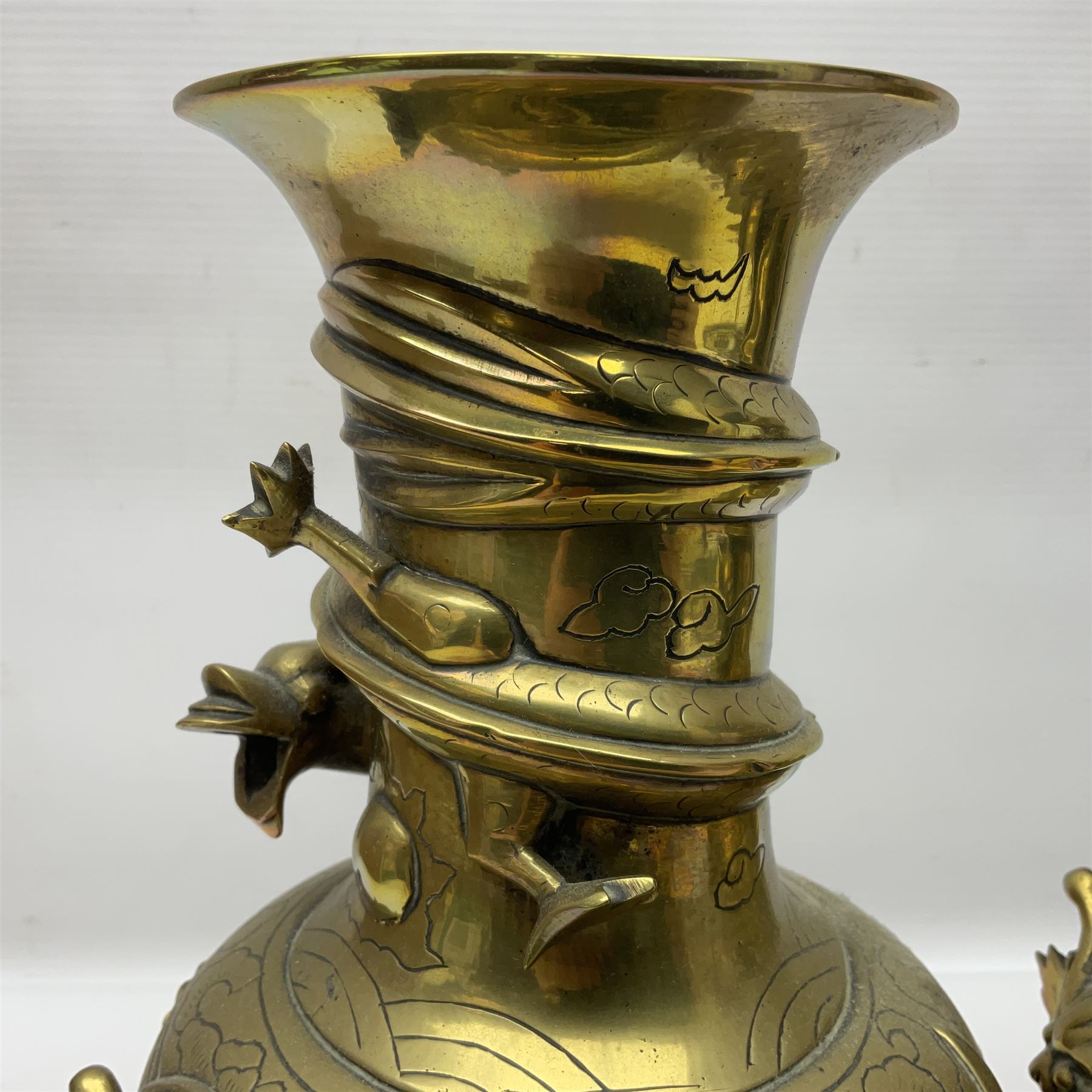 Pair of Chinese brass vases, of ovoid form with elongated neck and fluted rim, decorated in high relief with a dragon chasing a flaming pearl around the neck, the body with dragons, birds and buildings, with character marks beneath, H25cm