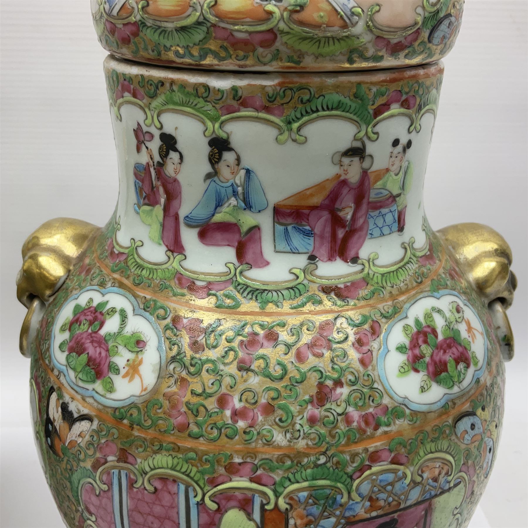 Pair of 19th century Chinese Famille Rose vases and covers, each of baluster form with twin gilt lion mask ring handles to shoulders, the flattened domed covers with gilt temple lion finials, each decorated with alternating reserves of bijin and attendants, and birds and butterflies amongst blossoming peonies, against a gilt ground profusely decorated with stylised scrolls, H32.5cm