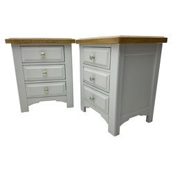 Pair of painted bedside chests with oak top, fitted with three drawers, raised on square supports with shaped apron, in cream finish