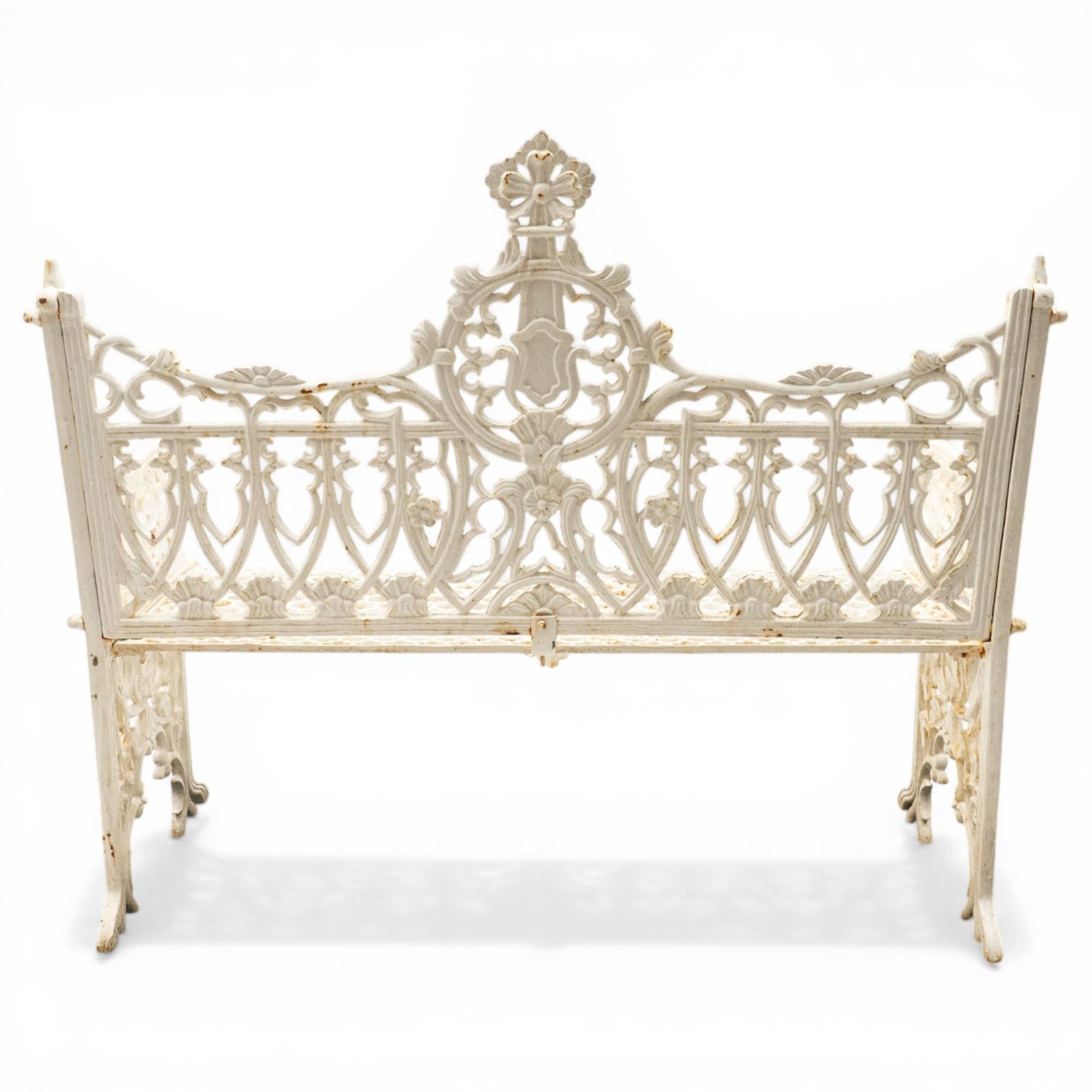 Victorian revival heavy cast iron garden bench, ornate back rest with scrolls, floral motifs and central crest, pierced lattice seat, curved arms and decorative legs, painted in antique white, in the Gothic Coalbrookdale style
