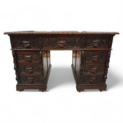 Victorian carved oak twin pedestal desk, moulded and foliate carved rectangular top with leather inset, fitted with nine drawers, each carved with scrolling foliage and lion mask handles, on skirted base 