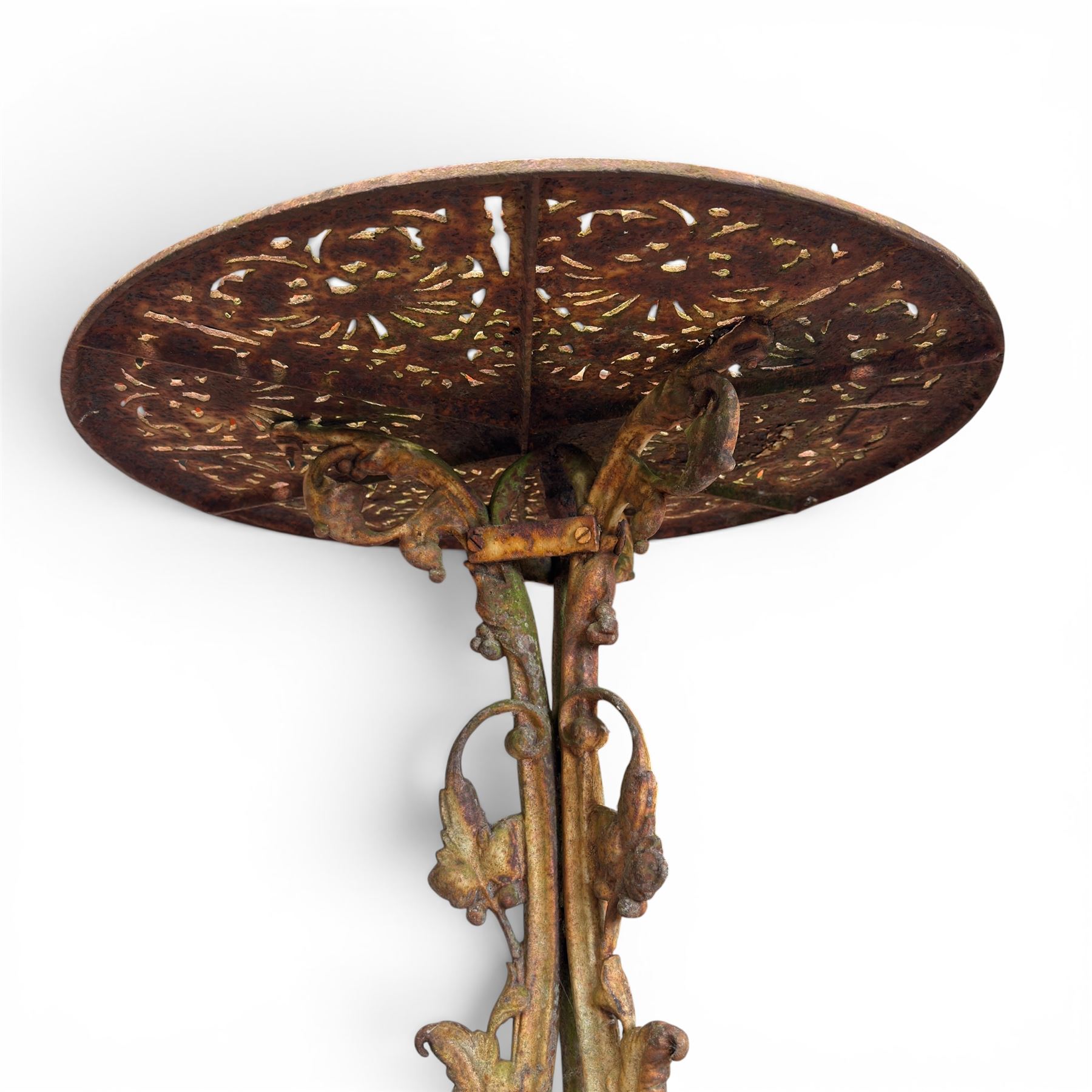 Victorian cast iron garden table, circular pierced top with foliate and scroll decoration, raised on an ornate tripod base with natural weathered paint finish.