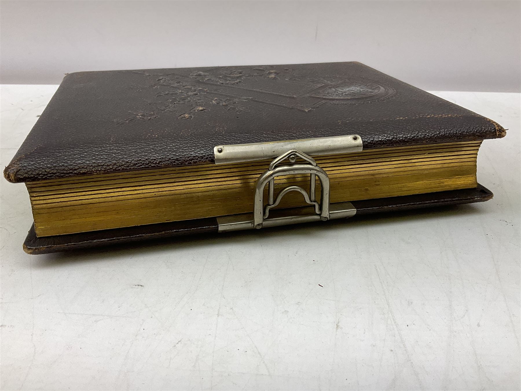 Victorian leather bound photo album, the interior leaves containing apertures of various sizes and shapes of portraits surrounded by printed floral designs, H28cm