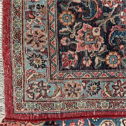 Meshed Persian rug, red, indigo, and teal background with repeating floral vine around a symmetrical floral medallion with bold palmettes, central ivory radiating floral centrepiece, and spandrels, indigo and teal border of delicate scrolling palmette and leafy floral vines