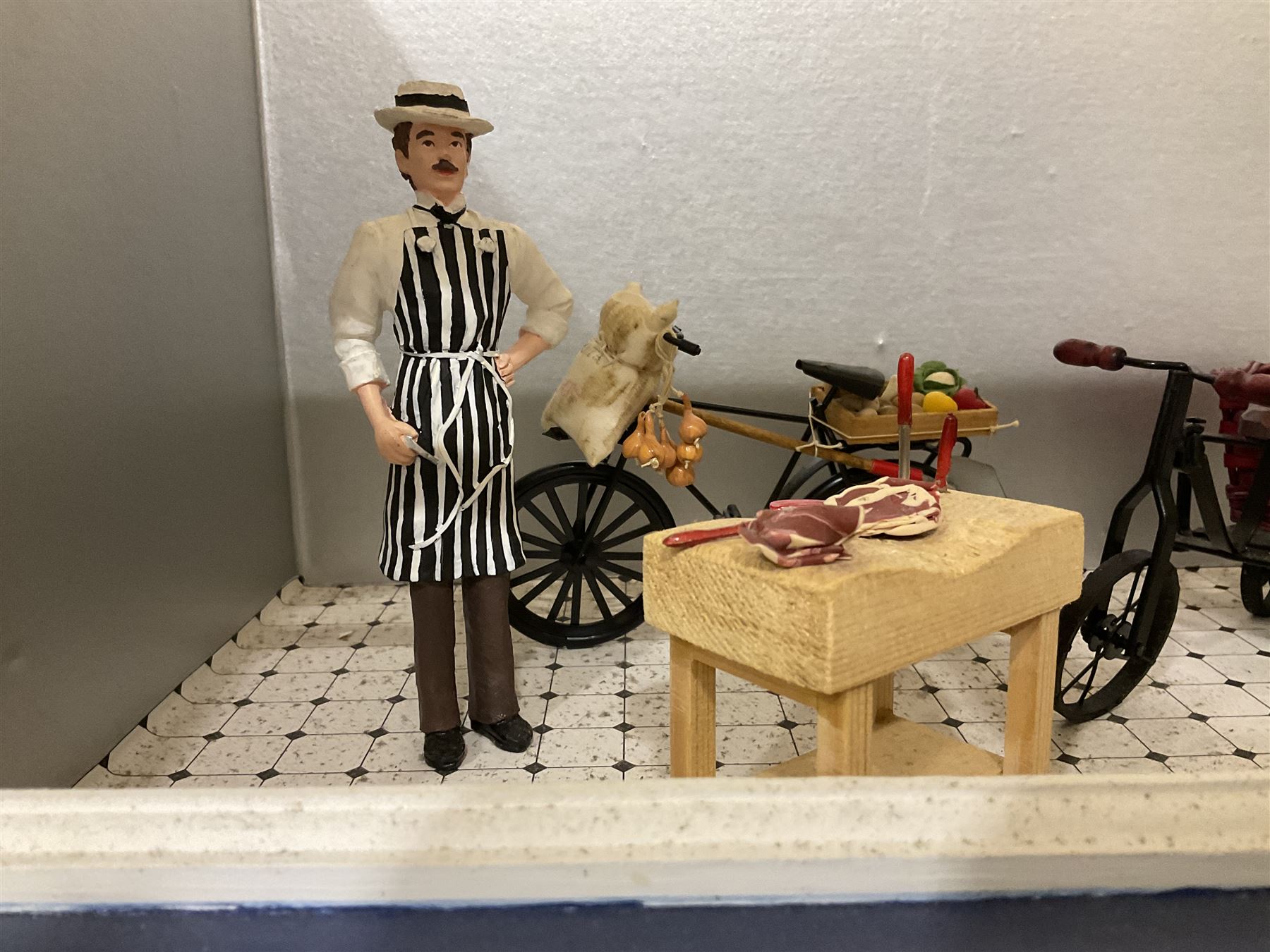 Three scratch-built wooden shop dioramas - single room Pet Shop with hinged front, fully furnished and well stocked with animals, birds and numerous accessories; and matching Garden Shop, fully furnished and well stocked with fruit, vegetables and garden accessories including lawn mower, wheelbarrows etc; each W34cm H27cm D26cm; and double fronted single room Butchers Shop with butcher at his block, partially stocked counter and two delivery cycles W57cm (3)