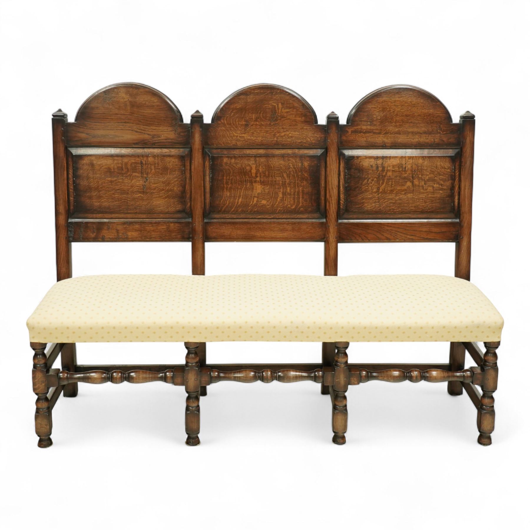 Bylaw of Ross On Wye - 17th-century design oak three-seat hall bench, triple arched panelled back, padded seat upholstered in a yellow herringbone ground fabric with star motif, raised on turned baluster legs united and turned front stretcher