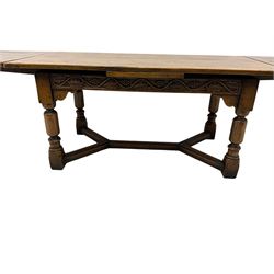 Early 20th century Jacobean design draw-leaf oak dining table, rectangular top with carved frieze depicting scrolling foliage and grape clusters, sliding extending leaves, raised on robust turned supports united by H-stretcher  